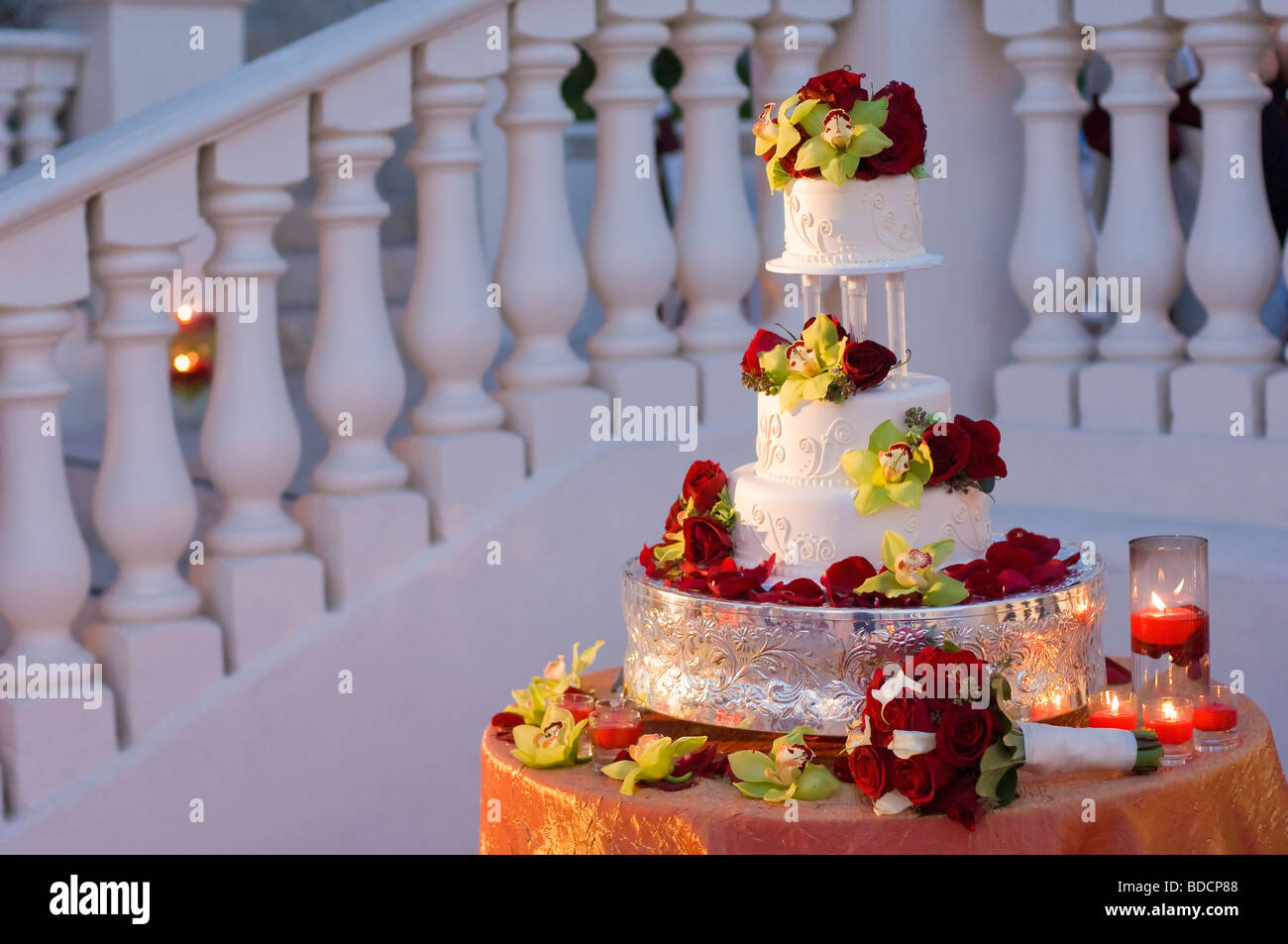 White wedding cake with red roses and green orchids Stock Photo