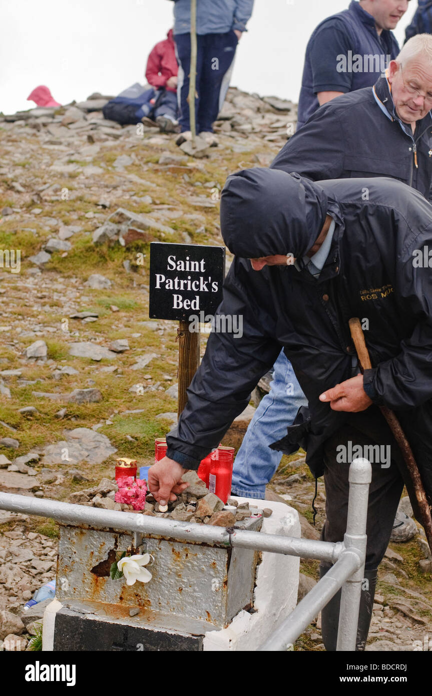 Pilgrim with walking stick makes offering on the summit of Croagh Patrick on Reek Sunday, 25th July 2009 Stock Photo