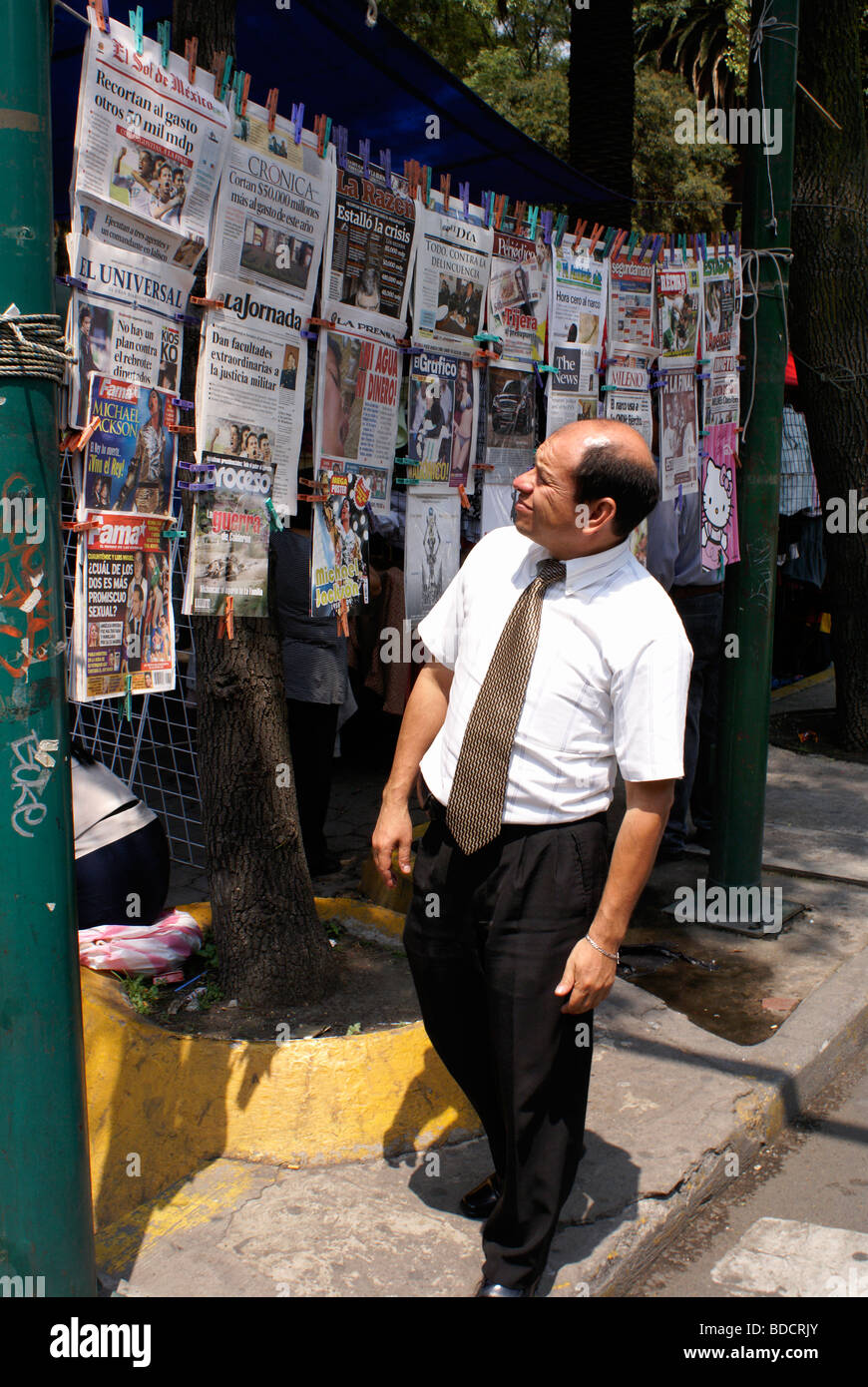 Man looking at Spanish language newspapers and magazines at a newsstand in Mexico City Stock Photo