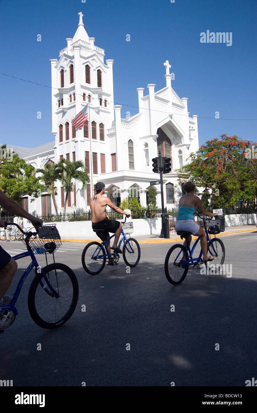 Bike riders passing St. Paul's on Duval Street in Key West Stock Photo