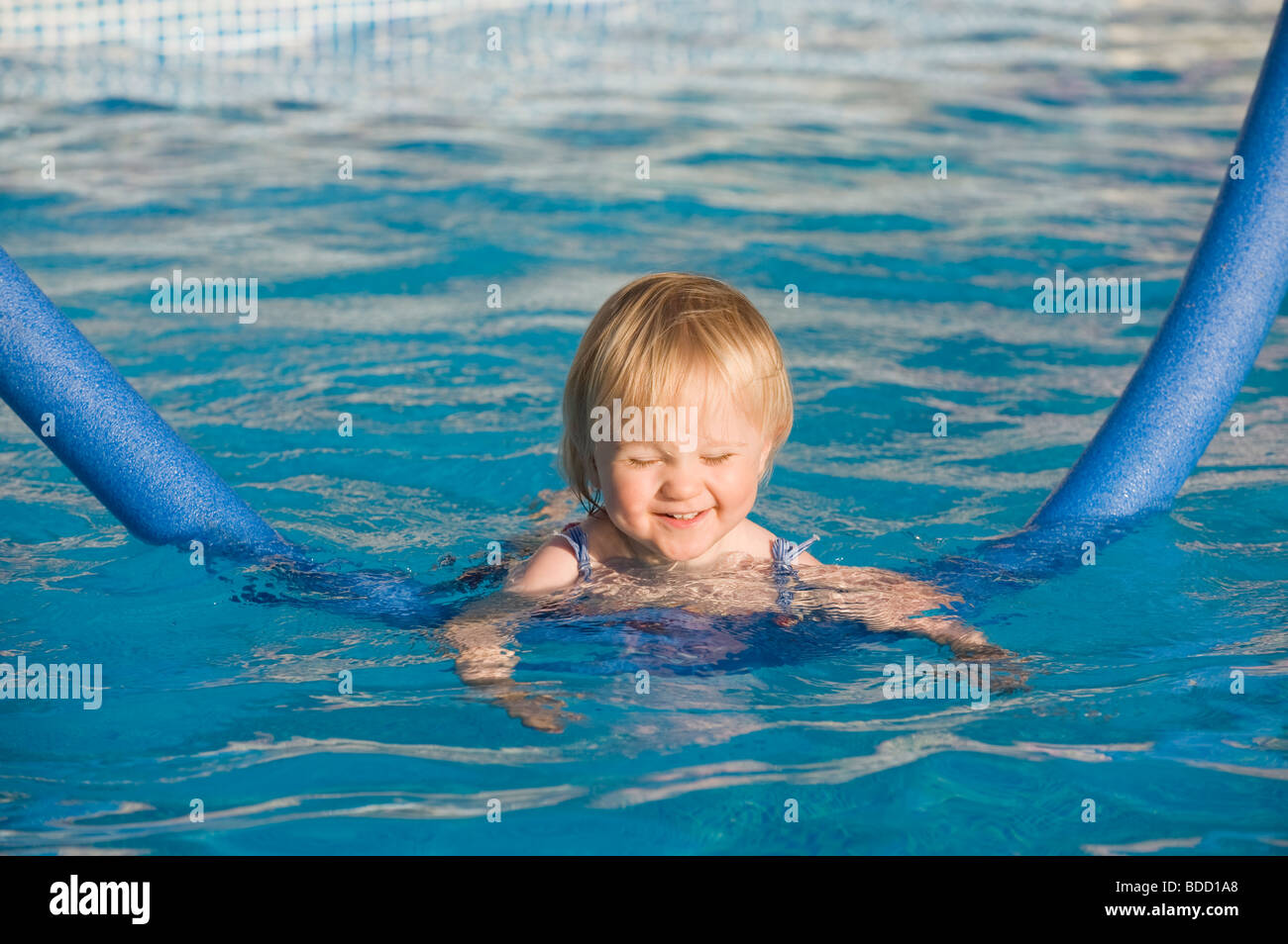 Baby girl learning to swim with aid of a noodle float Stock Photo Alamy