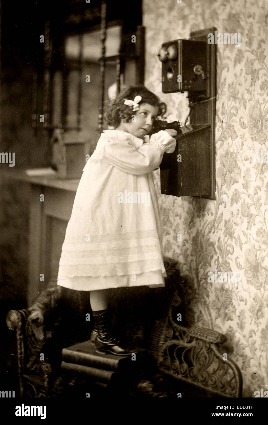 Little Girl Talking on Wall Telephone Stock Photo