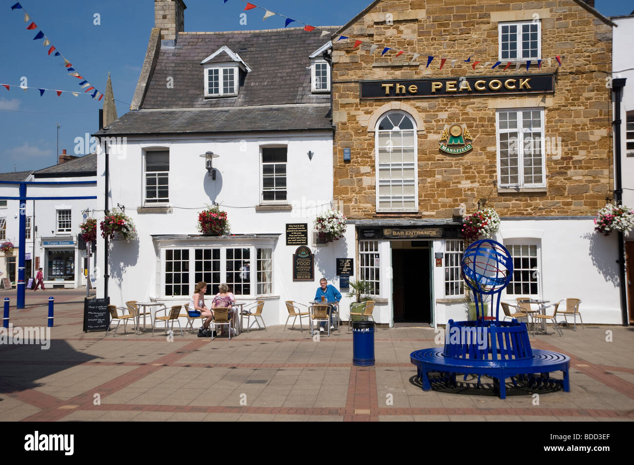 People sitting at tables outside a pub in the pretty market town of Market Harborough, Leicestershire Stock Photo