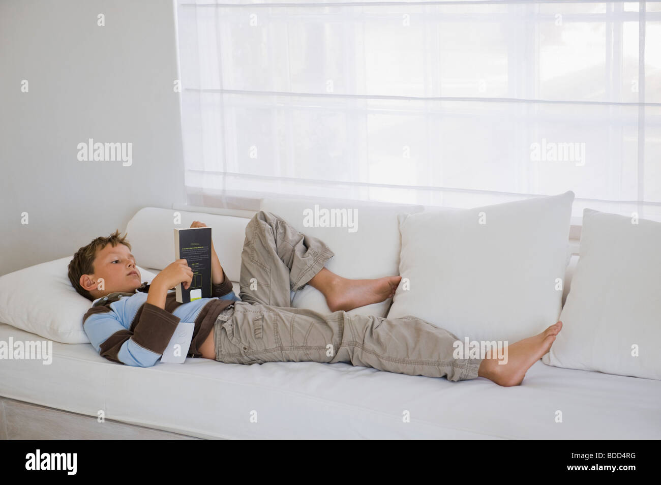Boy Lying On A Couch And Reading A Book Stock Photo 25490068 Alamy