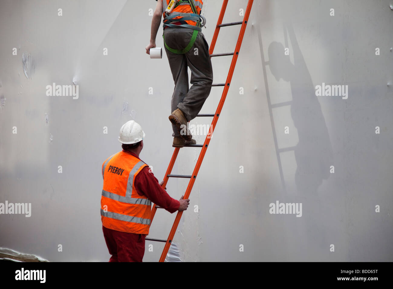 Workers working on a ladder. Health and Safety regulations may apply