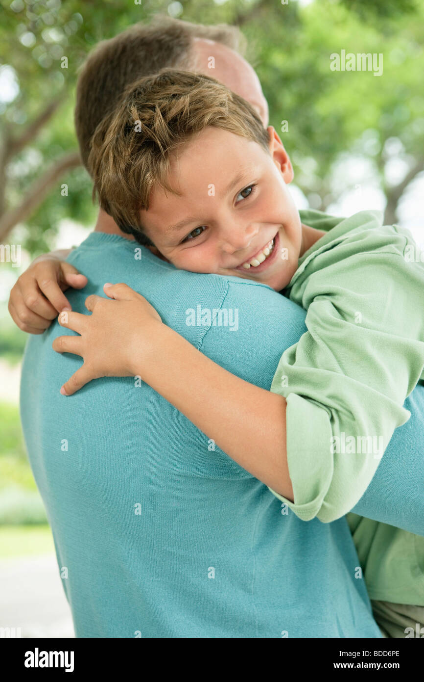 Boy hugging his father and smiling Stock Photo