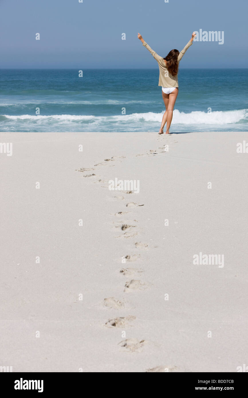 Rear view of a woman standing on the beach with her arms raised Stock ...