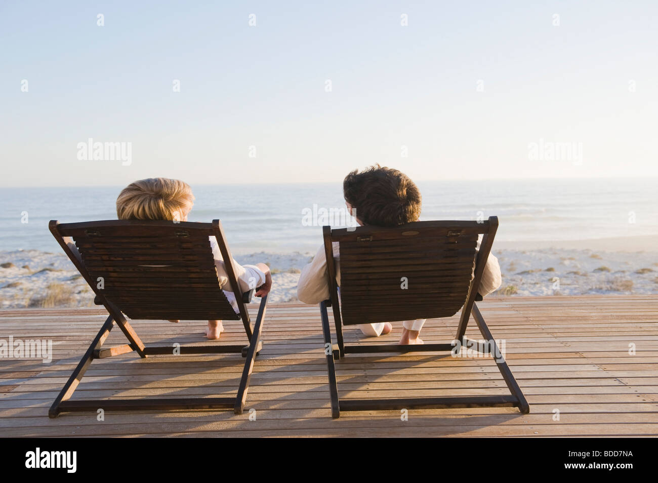 Couple reclining on deck chairs on the beach Stock Photo Alamy