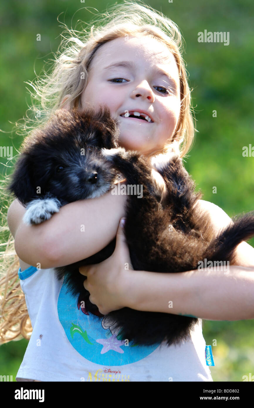 Smiling little girl hugging a big black dog in an outdoor setting Stock ...