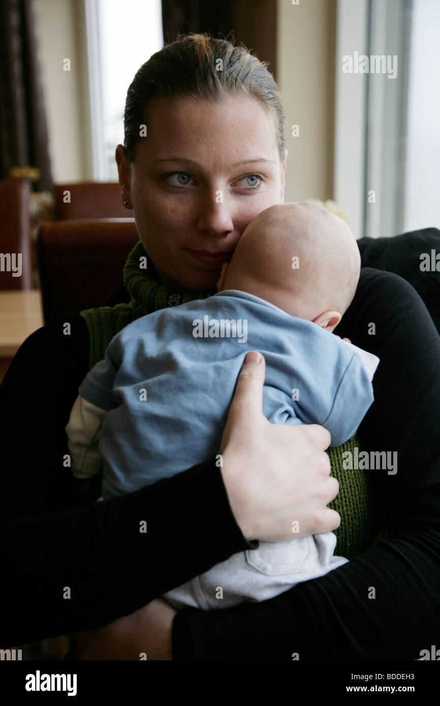 A two month old child is held by his mum sitting down. Model released Stock Photo