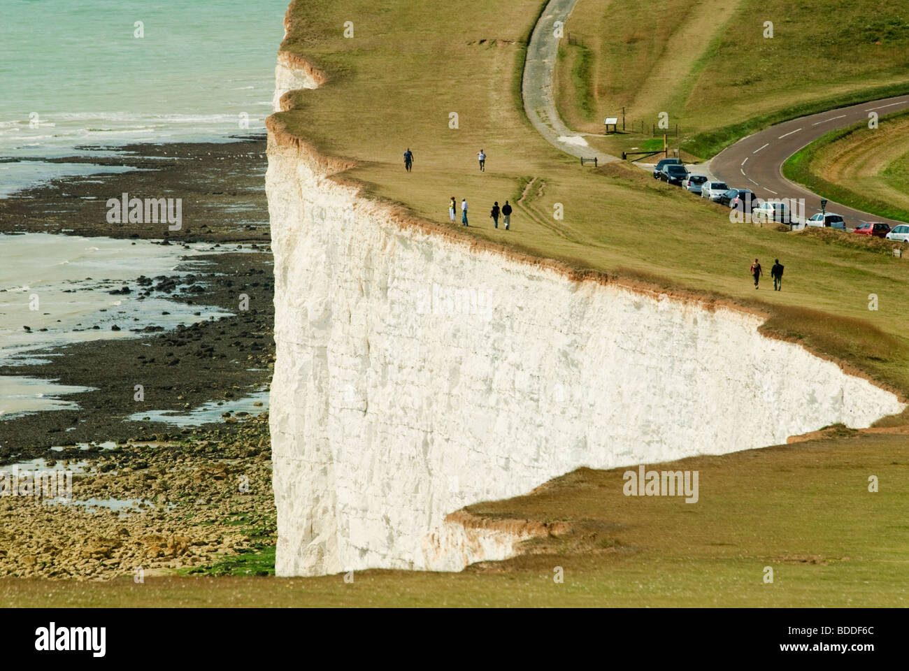 People walking near the edge of the white chalk cliffs at Beachy Head Eastbourne England looking out over the English Channel Stock Photo