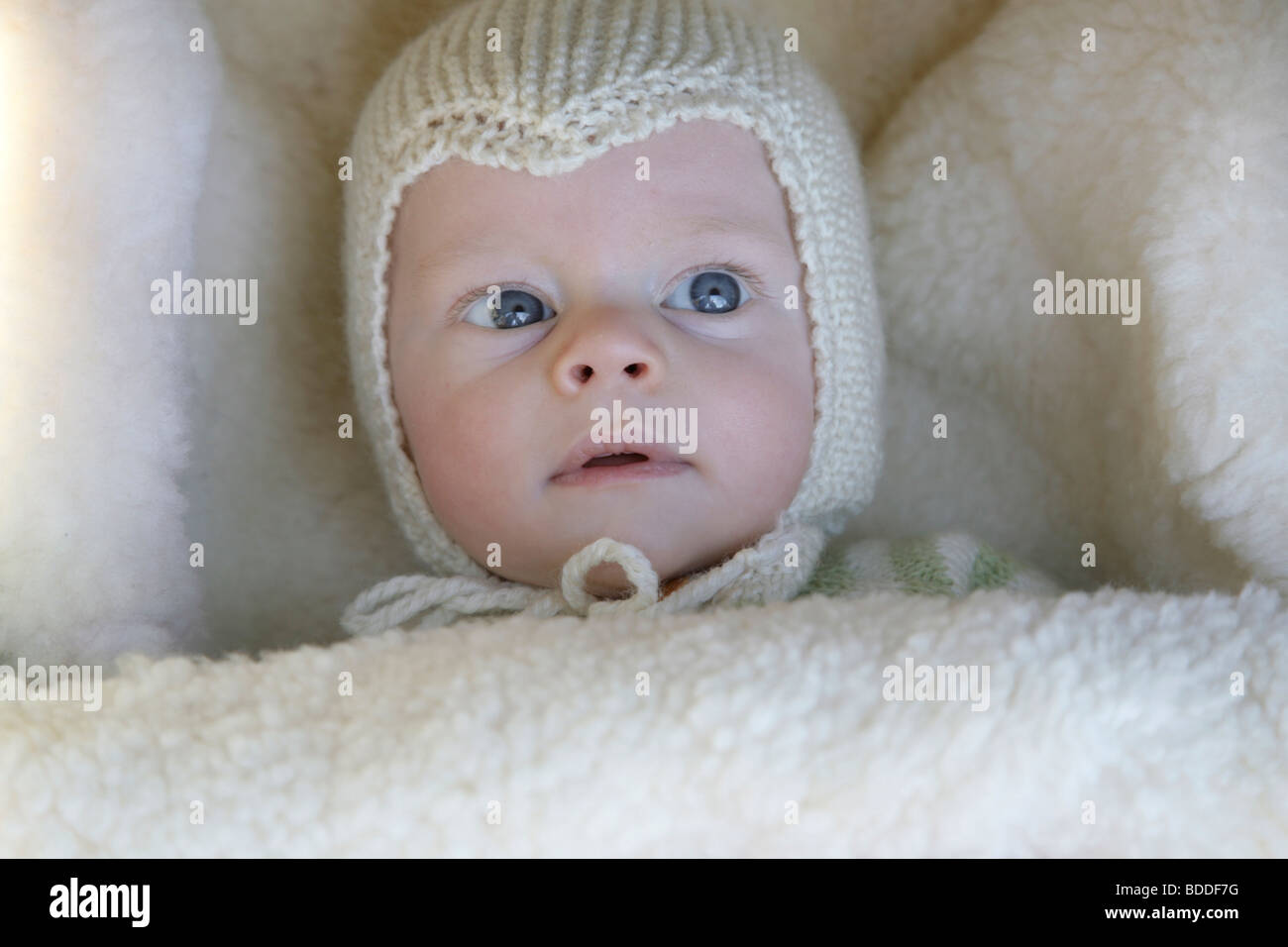 A four month old child wrapped up warm in a homemade knitted skull cap