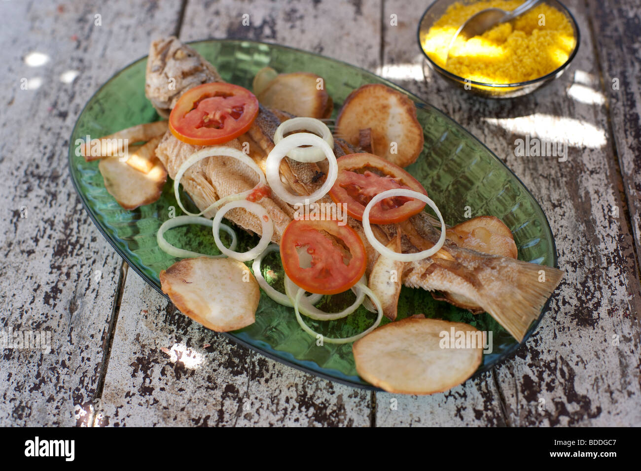 Whole fried fish with onion, tomatoes, potatoes chips and farofa Stock Photo