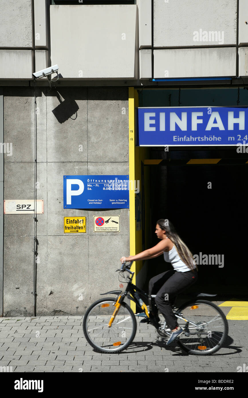 A cyclist going past a car park entrance in Munich, Germany. Stock Photo