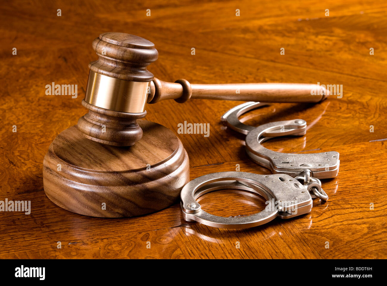 A gavel and block on a rich, cherry desktop with handcuffs. Stock Photo