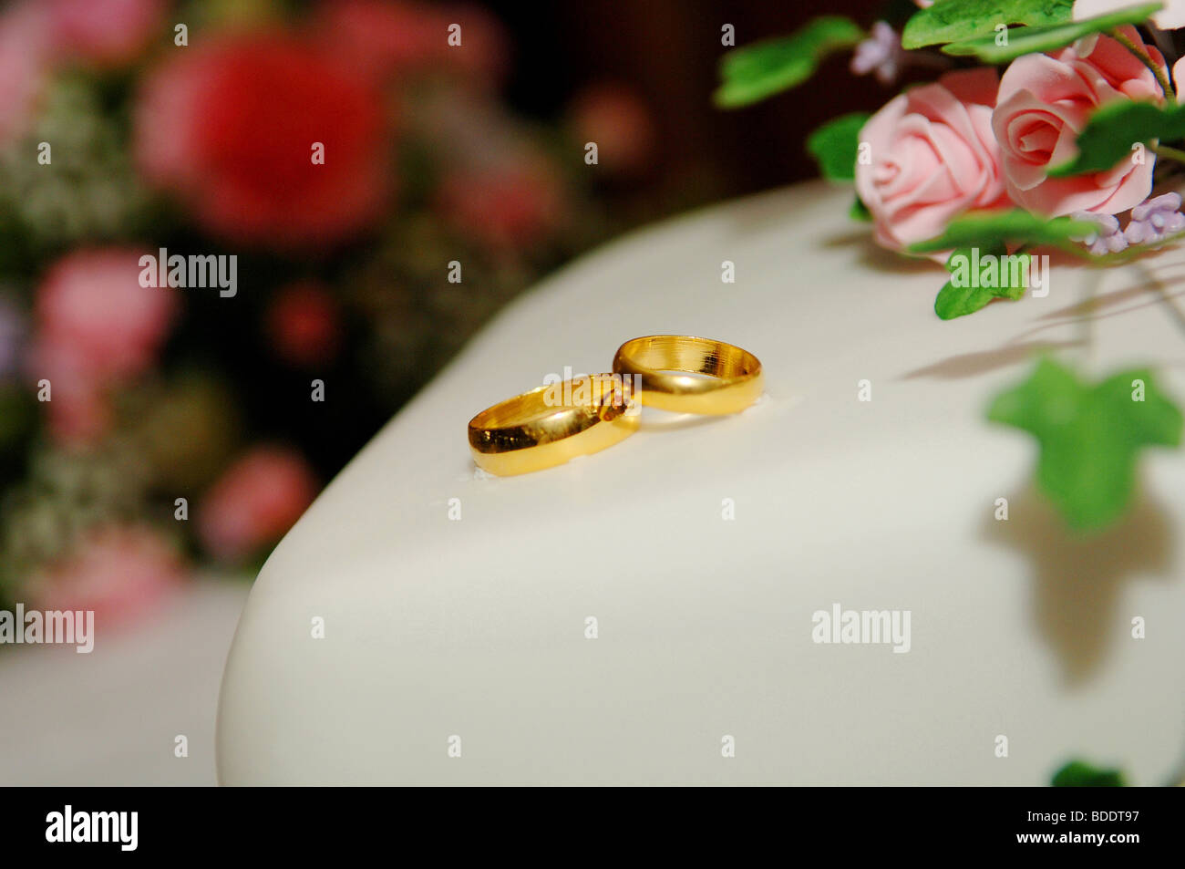 gold wedding rings on top of a wedding cake Stock Photo Alamy