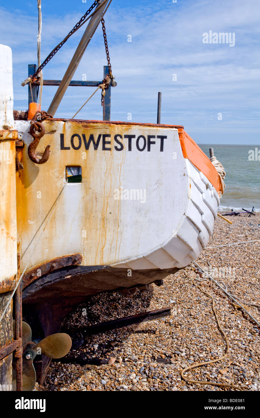 A small traditional wooden fishing boat (still in use) named 'Lowestoft' resting on the shingle beach at Aldeburgh, Suffolk, UK. Stock Photo