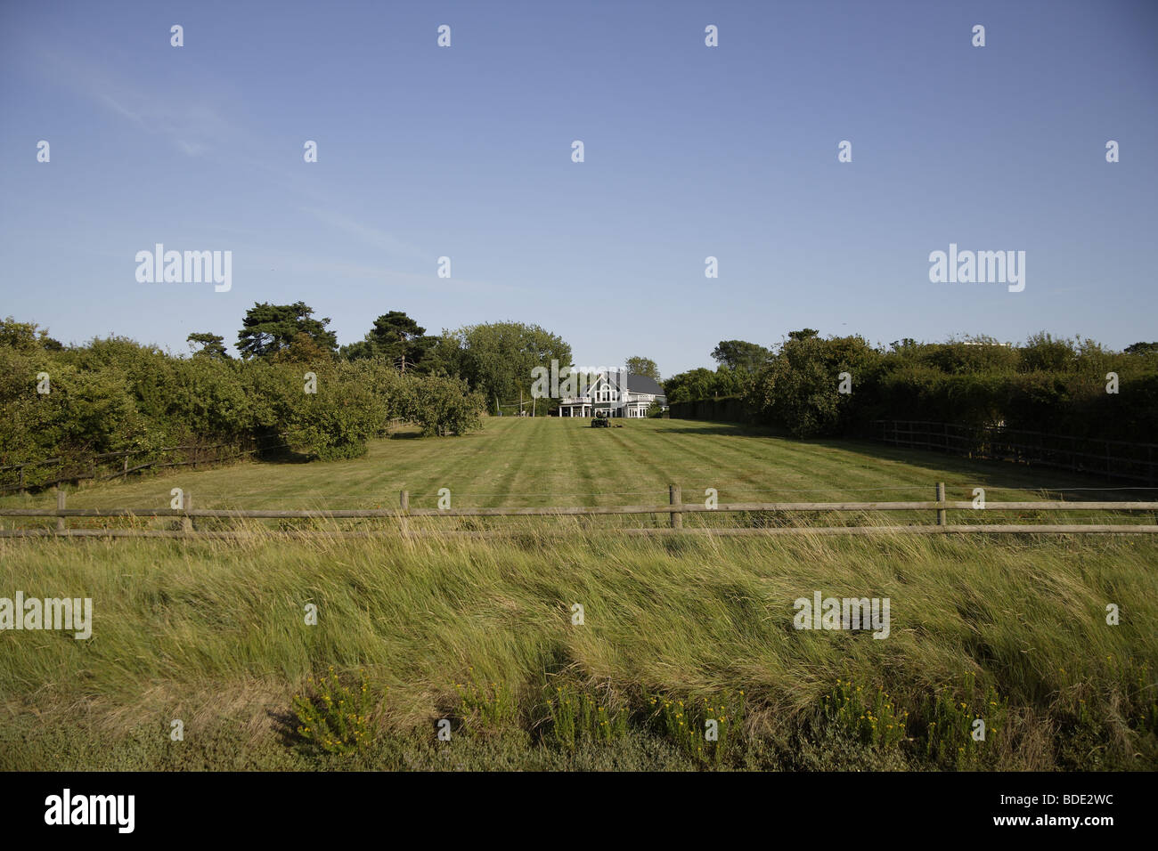 Sweeping lawns down to marshland with large house in the far distance,blue sky landscape Stock Photo