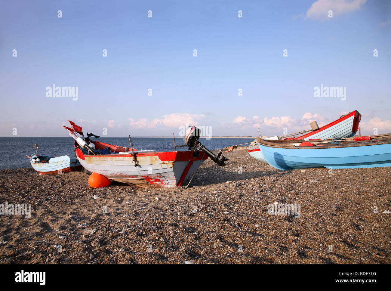 Coloured fishing boats pulled up on the beach at Klitmøller at sundown on the west coast of Jutland, Denmark. Stock Photo