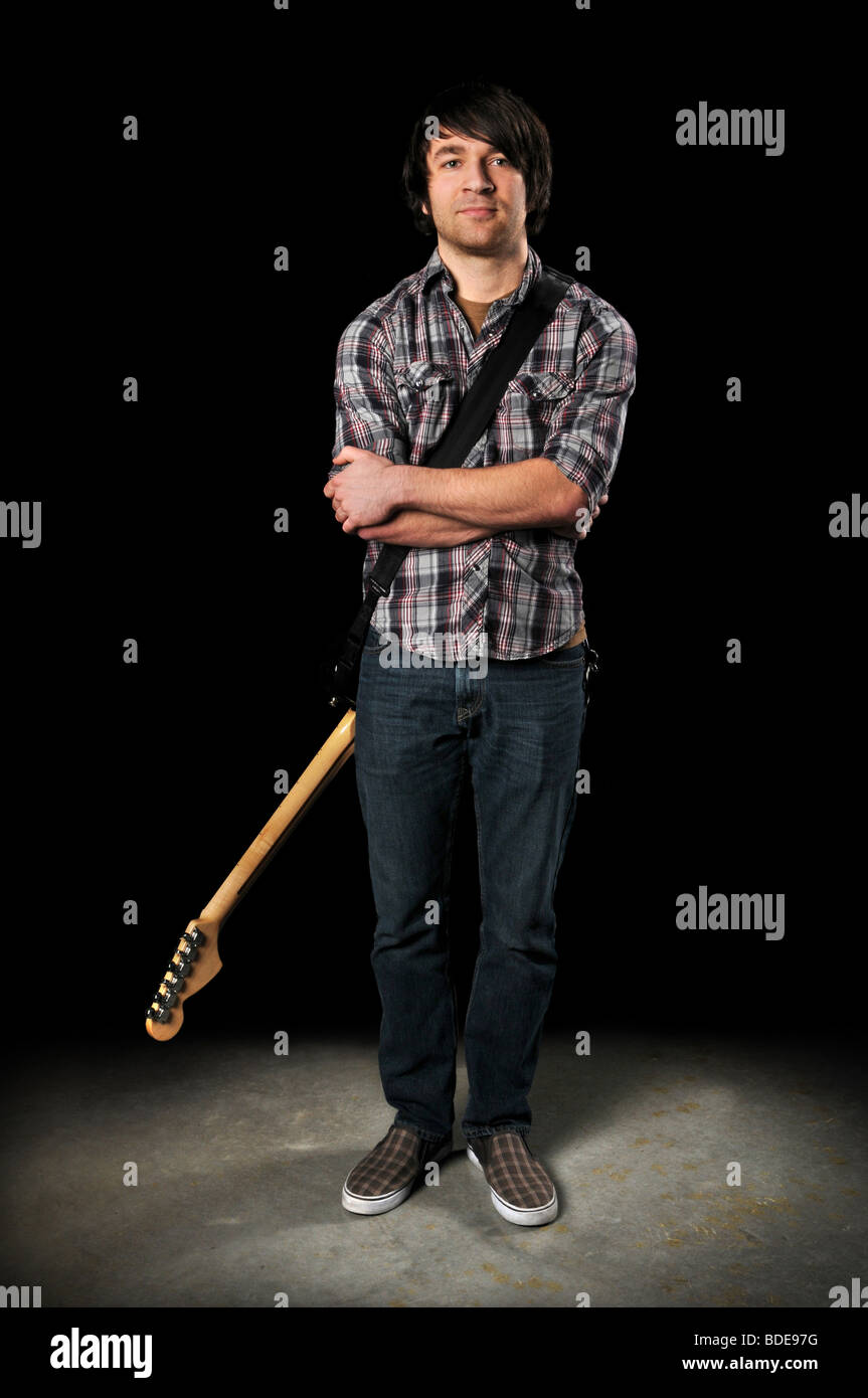Young man posing with electric guitar behind back Stock Photo