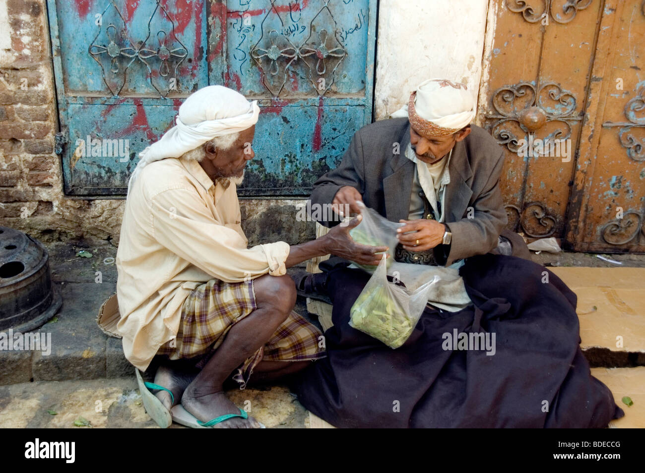 A man purchasing a bag of khat or qat - a chewable leafy stimulant and legal drug - from a merchant in the market in Sanaa, Yemen. Stock Photo