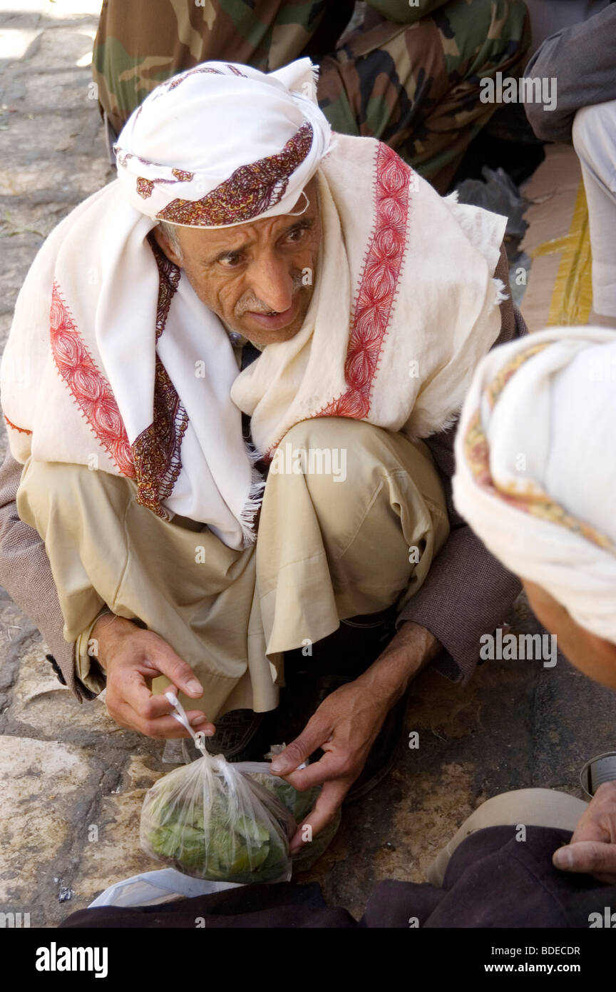 A man purchasing a bag of khat or qat - a chewable leafy stimulant and legal drug - from a merchant in the market in Sanaa, Yemen. Stock Photo