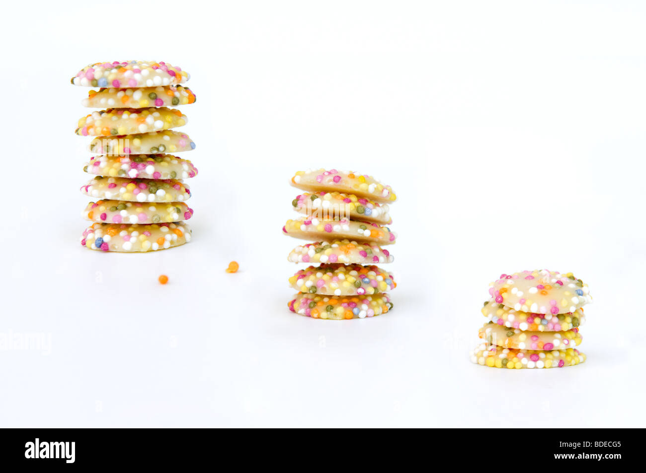 Still life artistic shot of white chocolate button sweets covered in sprinkles taken against a white background Stock Photo