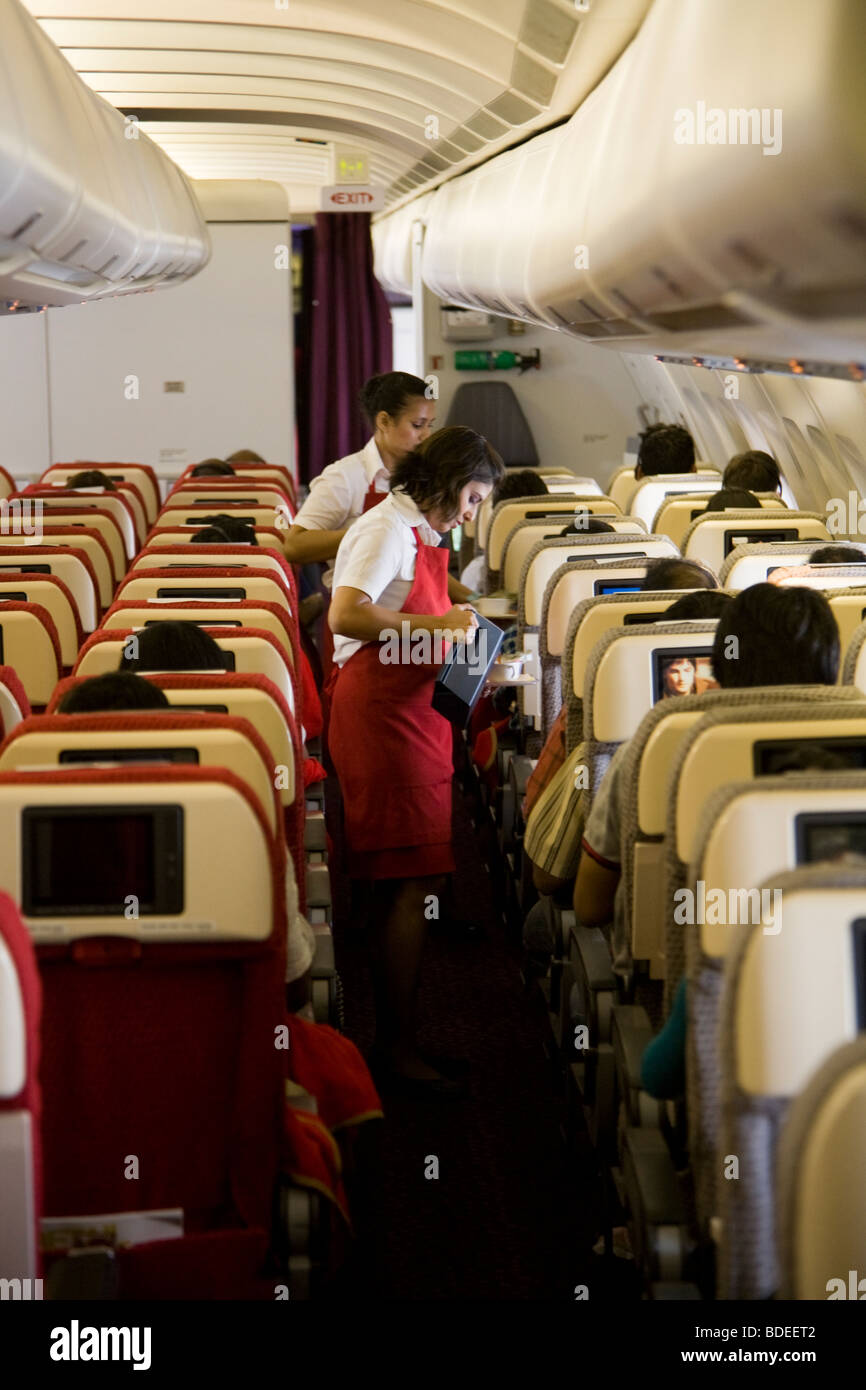 Member of cabin crew serving tea & coffee in the aisle on a Virgin Atlantic aircraft during flight to London from Mumbai, India. Stock Photo