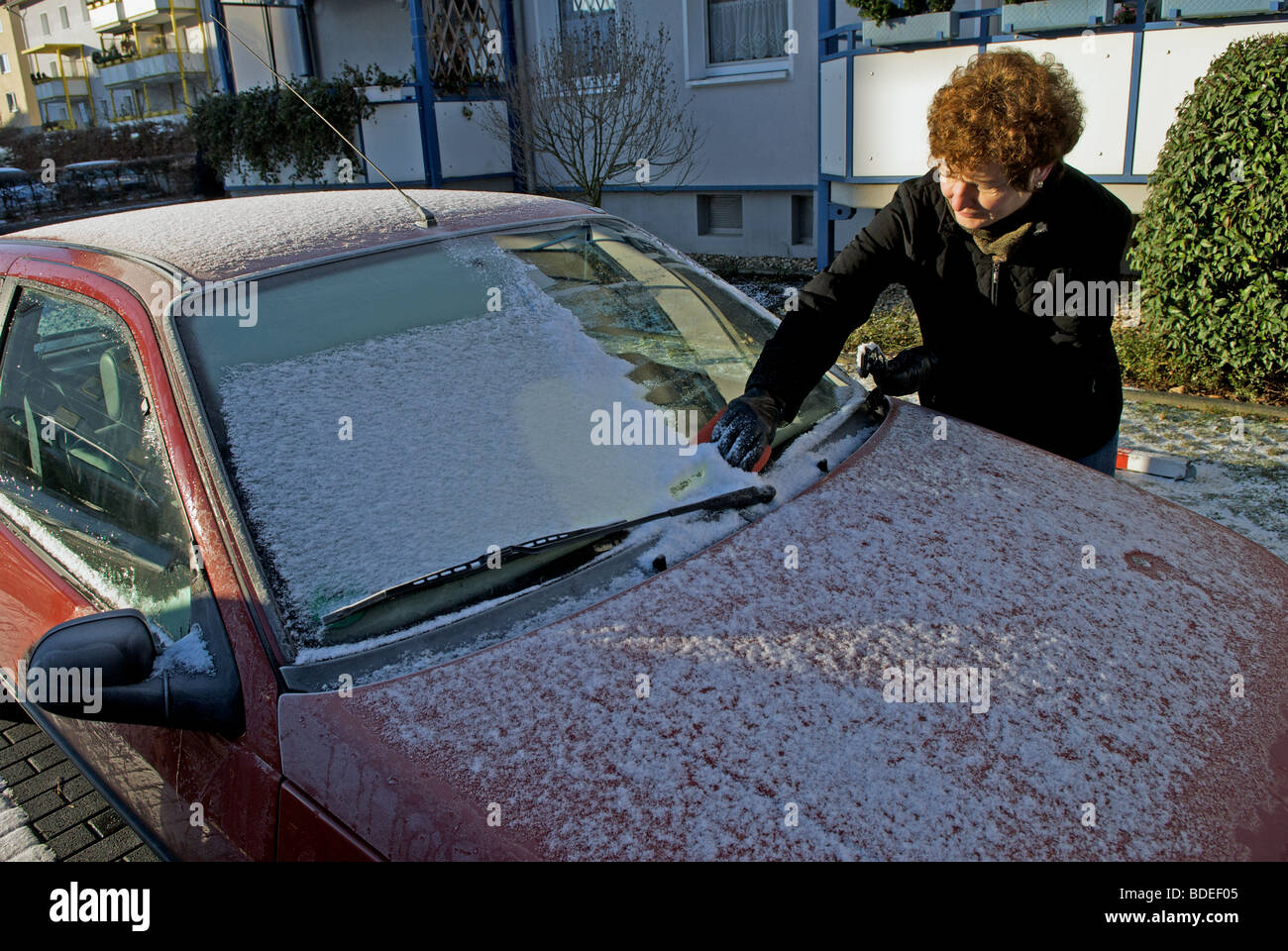 Driver clearing ice off a car window screen Stock Photo Alamy