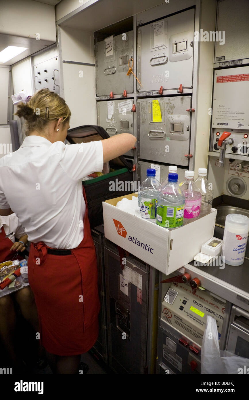Member of cabin crew with a box of soft drinks on a Virgin Atlantic aircraft during flight to London from Mumbai, India. Stock Photo