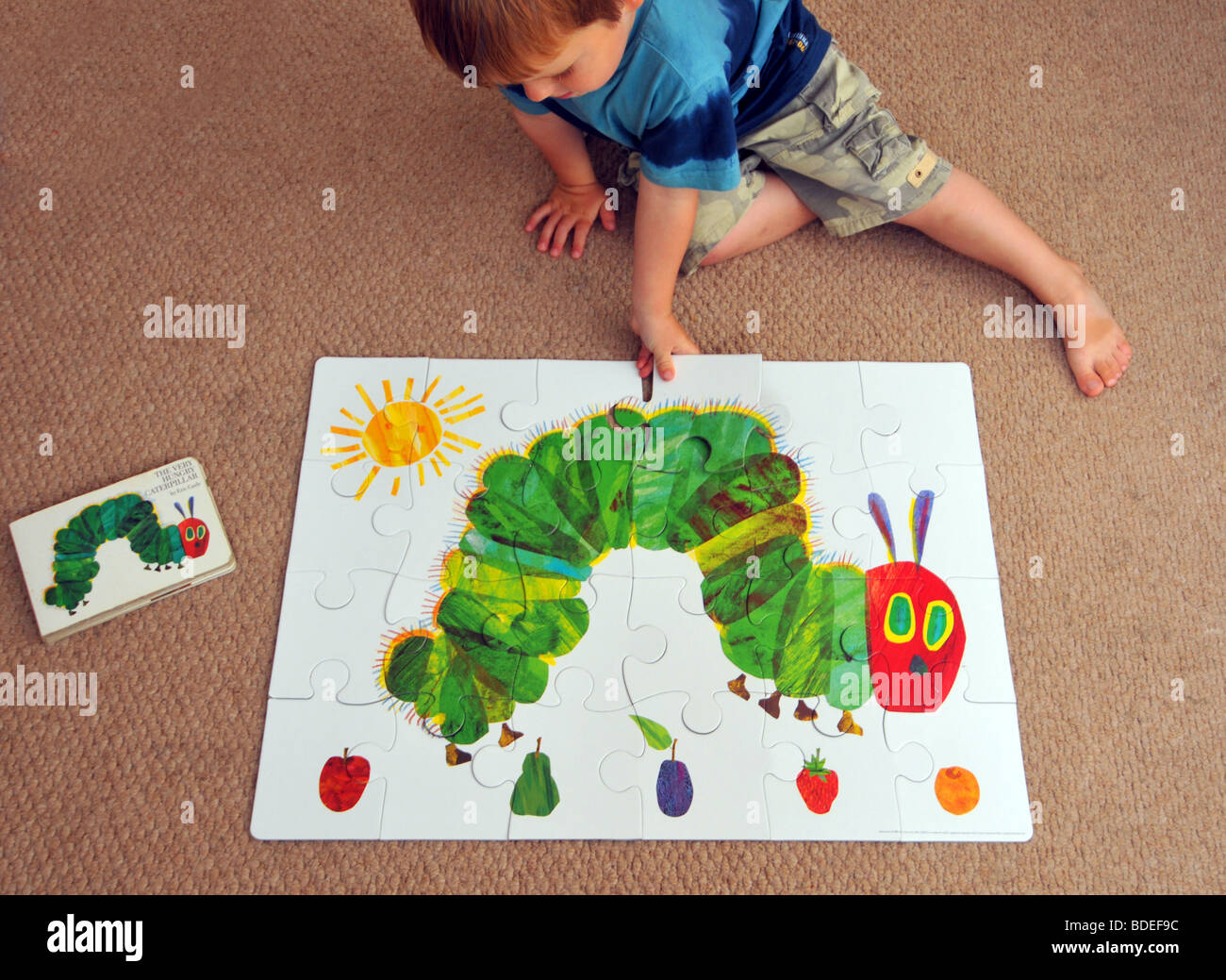 Child completes a jigsaw puzzle of The Very Hungry Caterpillar Stock Photo