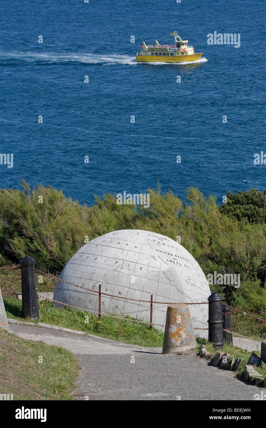 A tourist boat passes the Large Globe at Durlston Country Park, Swanage, Dorset, UK Stock Photo