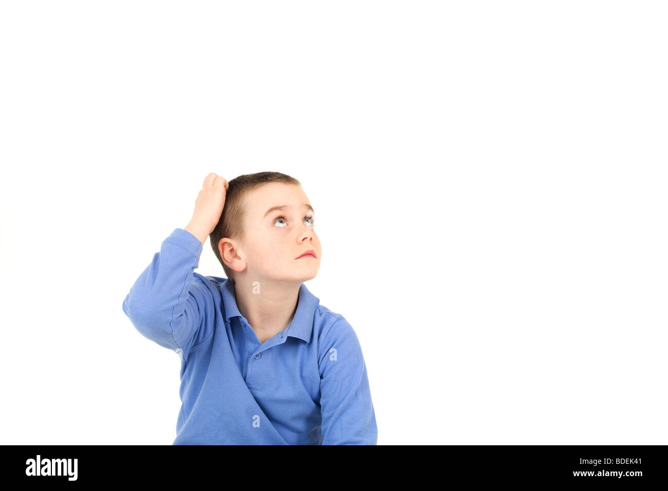 Young boy scratching head against white background Stock Photo