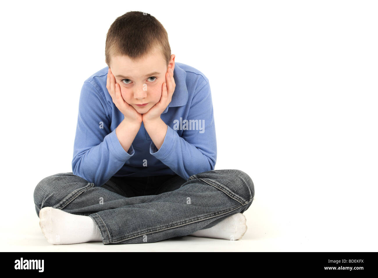 Portrait of young boy resting hand on chin against white background Stock Photo