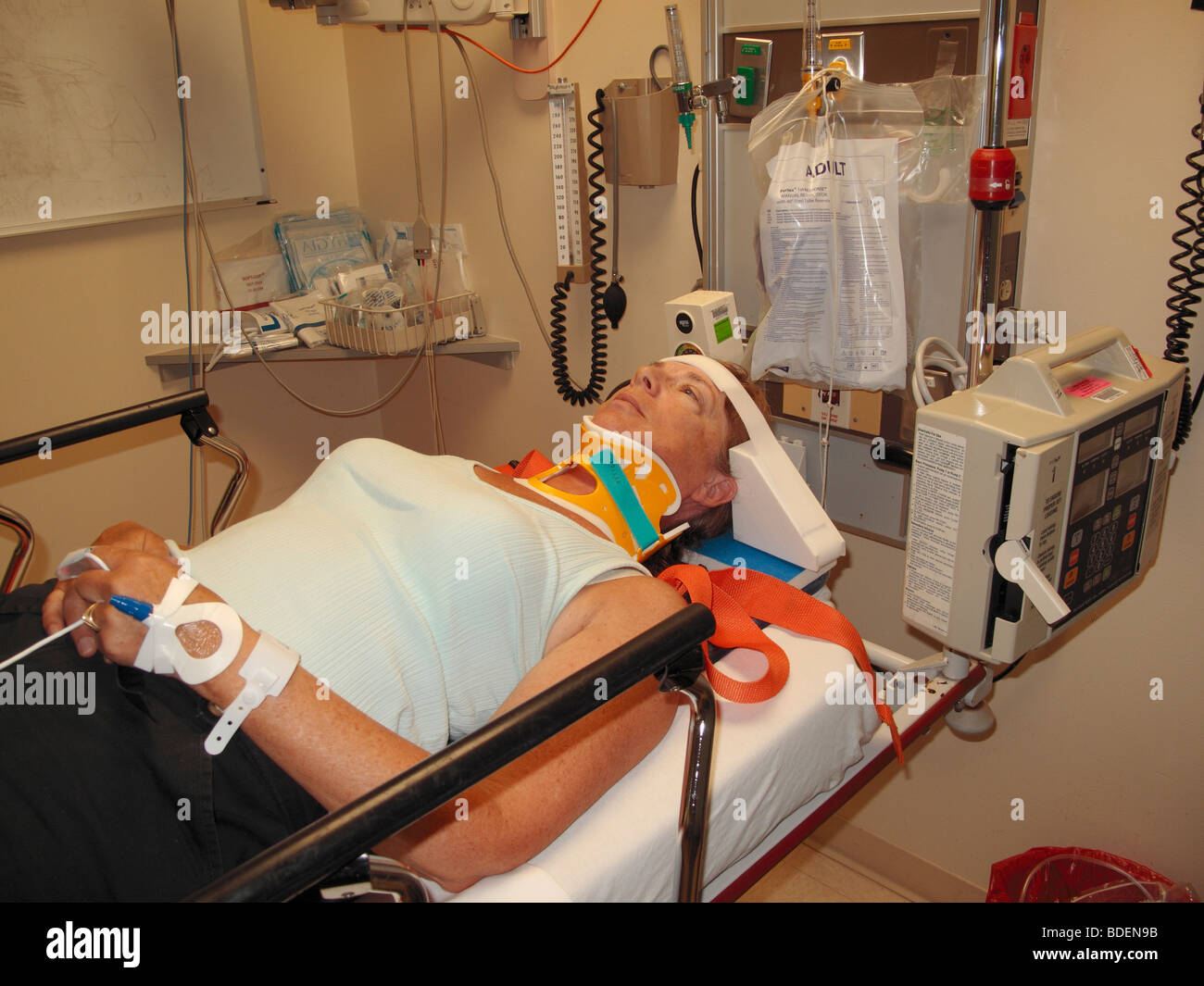 A woman who was in a car accident in a hospital emergency room restrained on an examination table with neck restraint Stock Photo