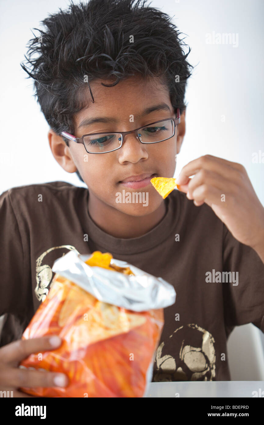 Teenage boy is eating corn chips Stock Photo