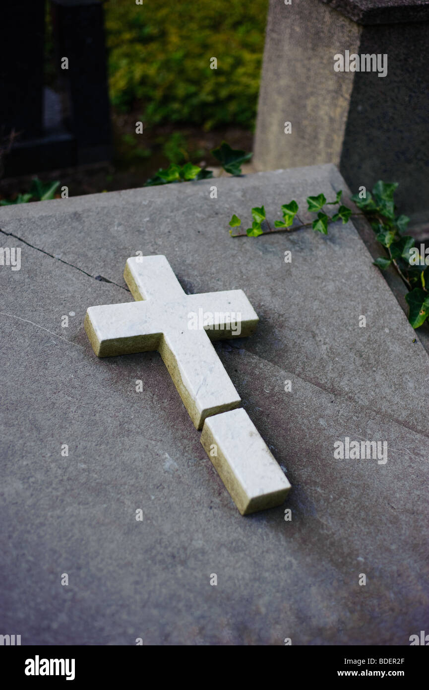 Broken tombstone with cross on a graveyard Stock Photo