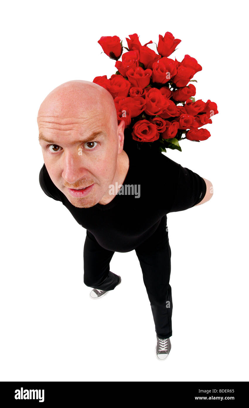 bald headed man hinding a bunch of red roses behind his back Stock Photo