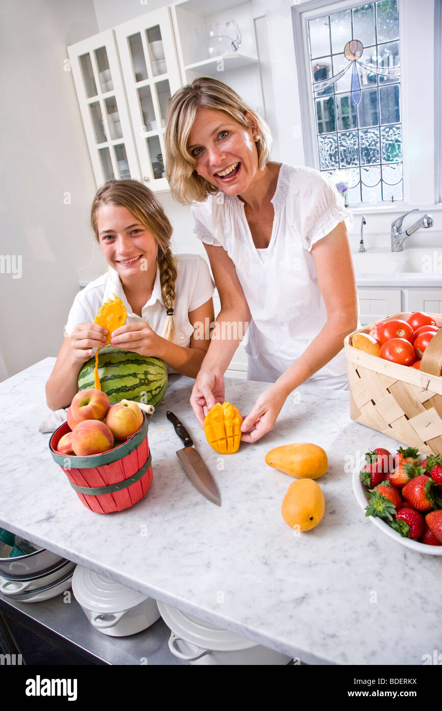 Mother and teen daughter cutting fresh fruit in kitchen Stock Photo Alamy