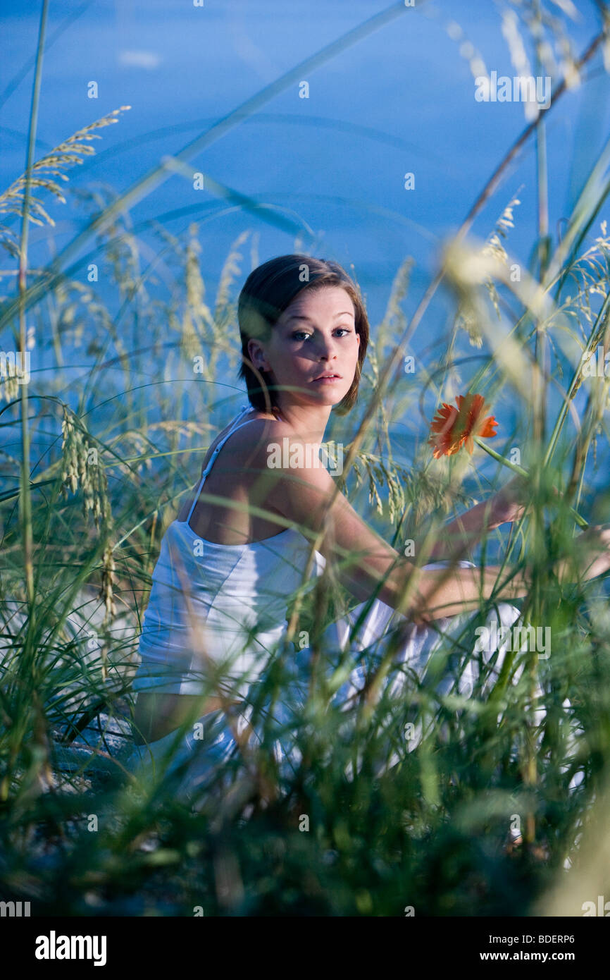 Pretty young woman sitting on beach in sand dunes and sea oats Stock ...
