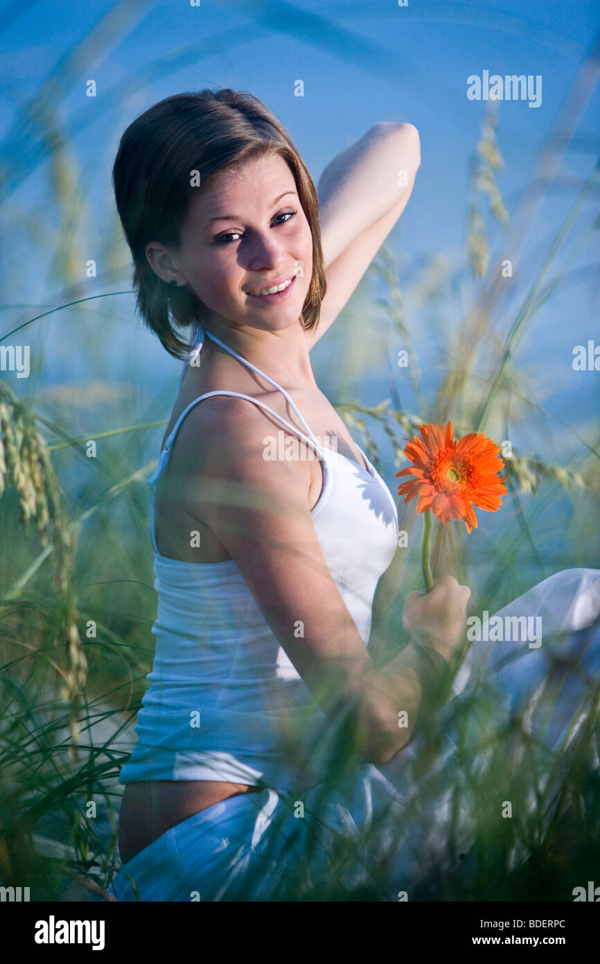 Pretty young woman sitting on beach in sand dunes and sea oats Stock ...