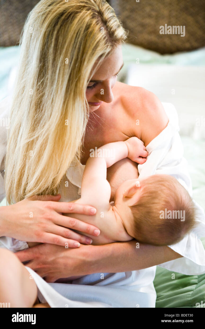 Young mother breastfeeding 6 month old baby in bedroom Stock Photo - Alamy