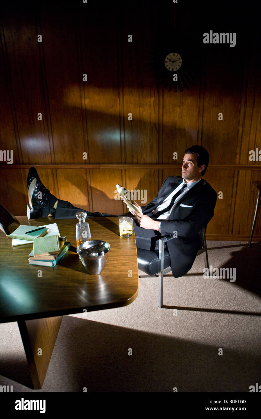 Vintage portrait of businessman relaxing with feet up on desk Stock Photo
