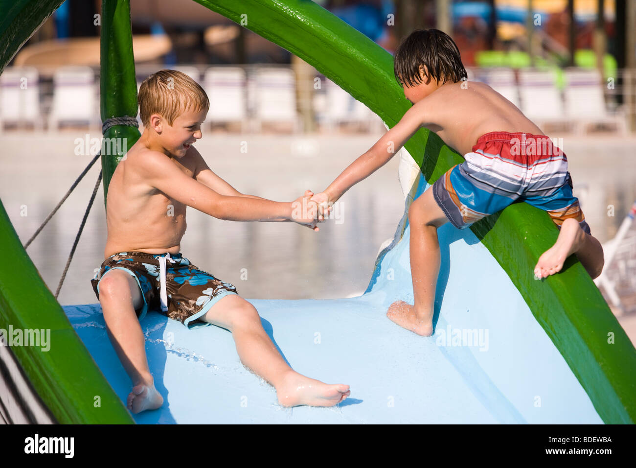 Two boys at water park in summer playing on slide near pool Stock Photo -  Alamy
