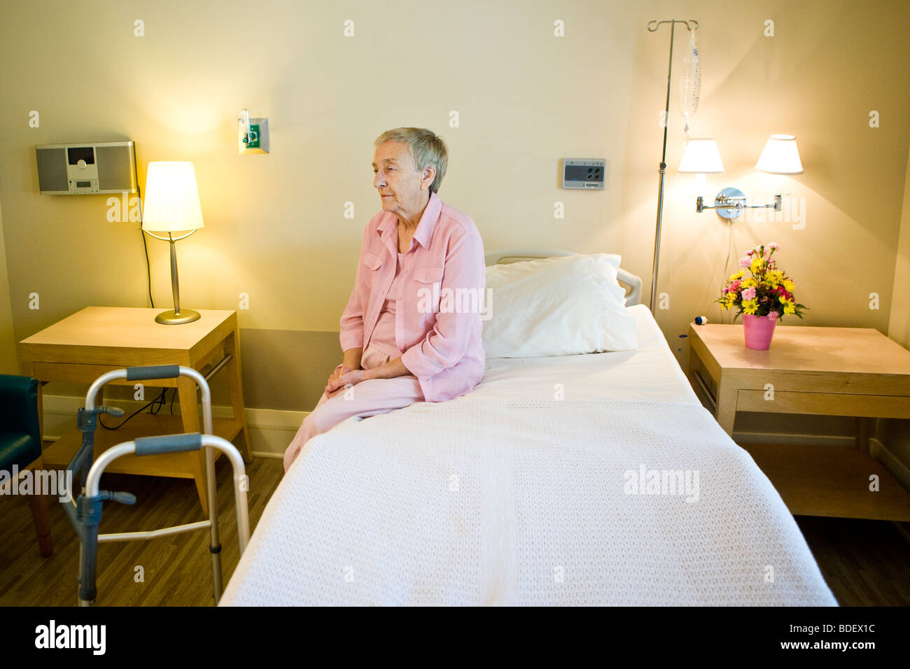 Elderly woman in nursing home sitting on bed Stock Photo
