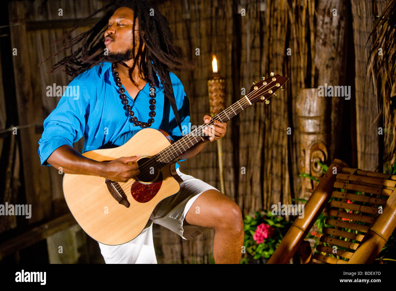 Young Jamaican man with dreadlocks playing guitar on tropical island Stock Photo