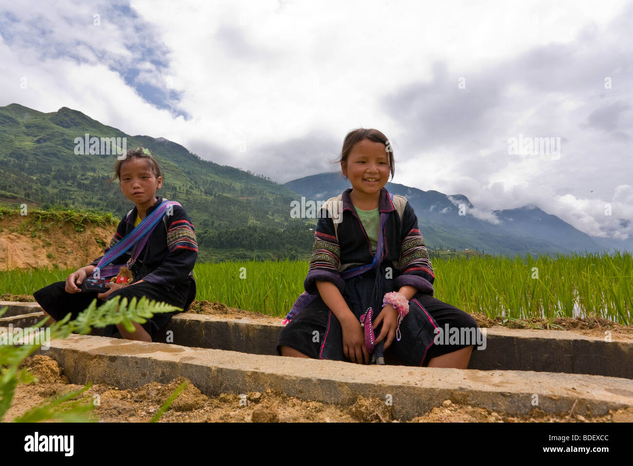 Local girls accompanying a group of hikers in the hope of selling handcrafts, Sa Pa, Vietnam Stock Photo