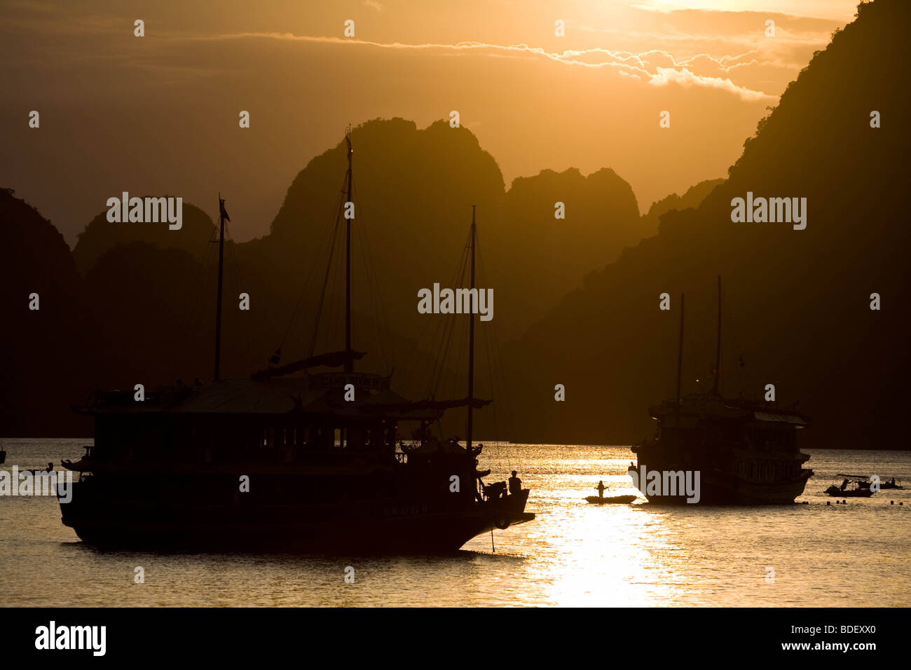 Tourist boats in the twilight among the limestone peaks of Ha Long Bay, Vietnam Stock Photo