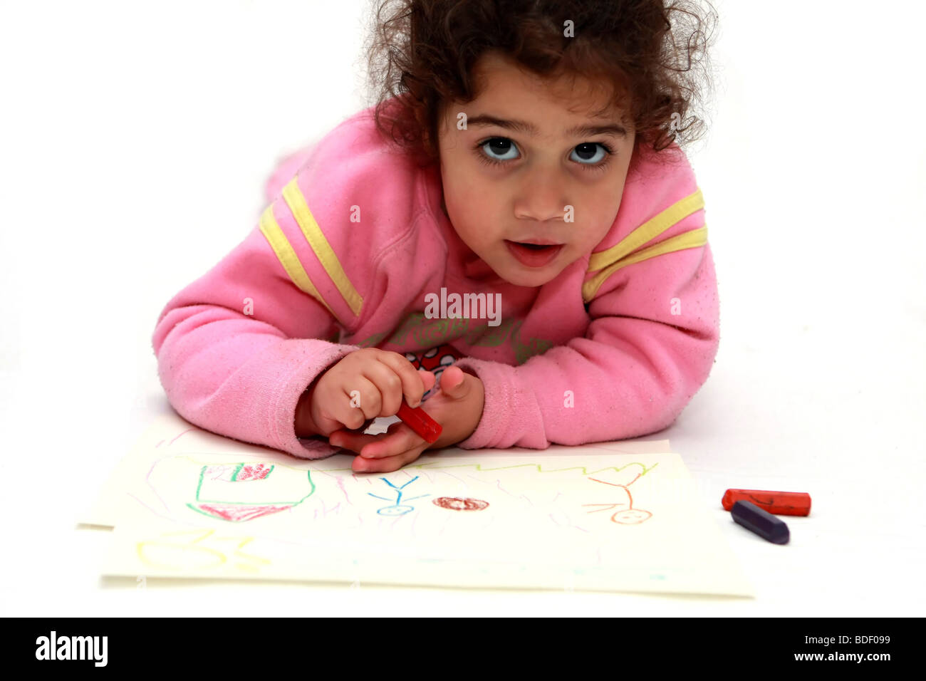 A young girl of three laying face down on the floor drawing Model