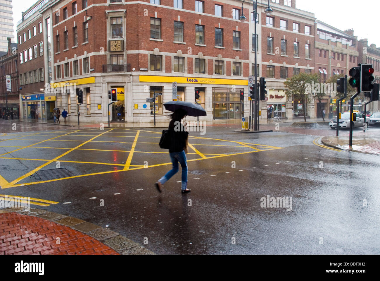 Woman with umbrella crossing road in rain Stock Photo - Alamy